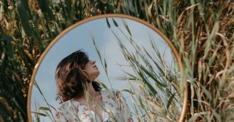 Self-Reflection - A woman in a field looking at a mirror