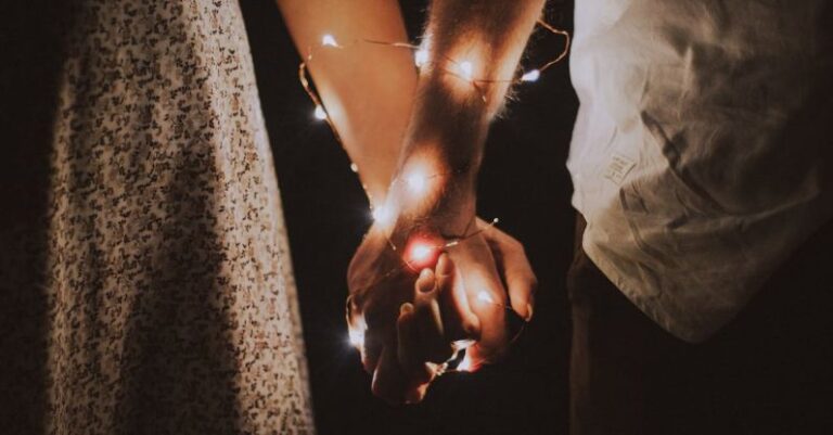 Couples - Man and Woman Holding Each Others Hand Wrapped With String Lights
