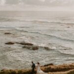 Walks - A bride and groom stand on a cliff overlooking the ocean
